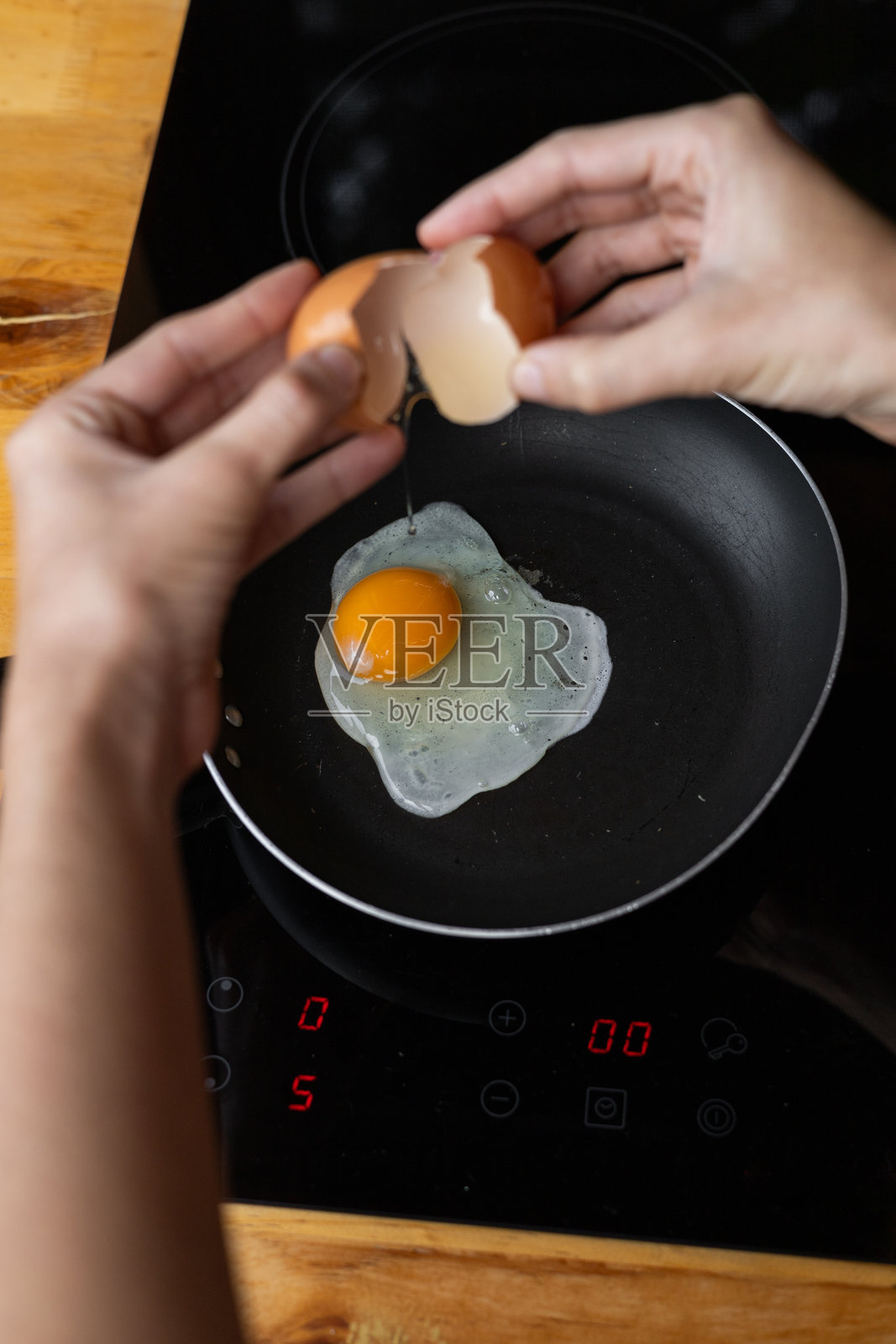 新鲜鸡蛋在热锅中煎炸，蛋黄完好无损，突显出滋滋作响的烹饪过程，展现出温馨厨房中美味自制早餐的开始。照片摄影图片