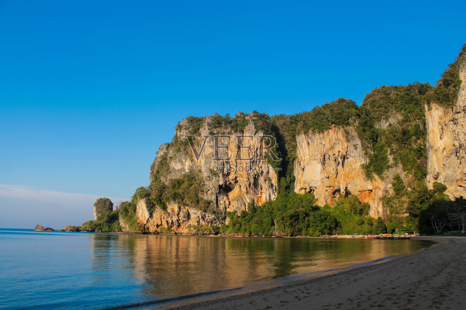 泰国甲米的悬崖和沙滩，碧蓝的海水、石灰岩地貌和热带植被在晴朗的天空下。照片摄影图片