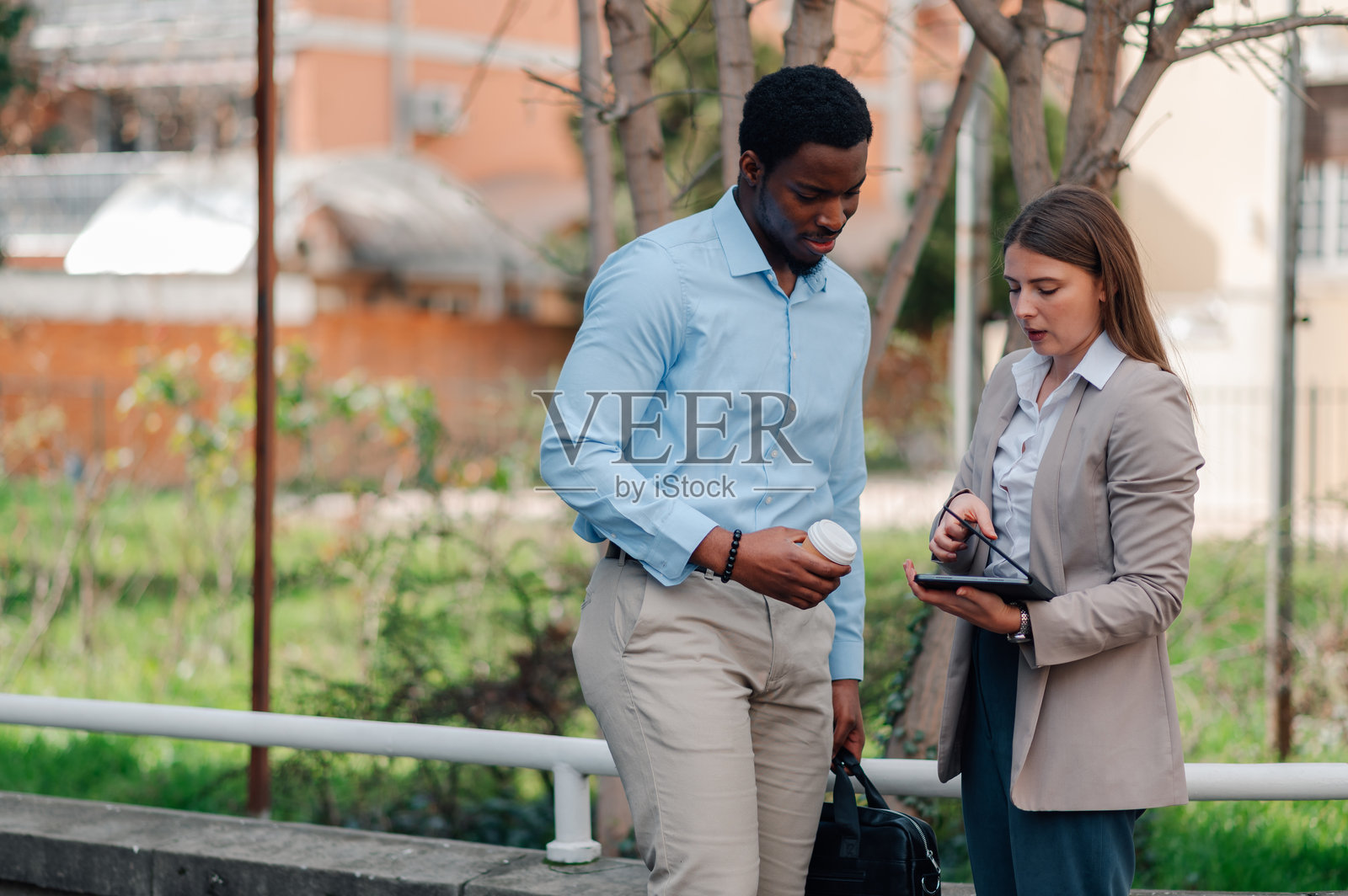 商务同事在户外讨论工作，手持平板电脑和咖啡。照片摄影图片