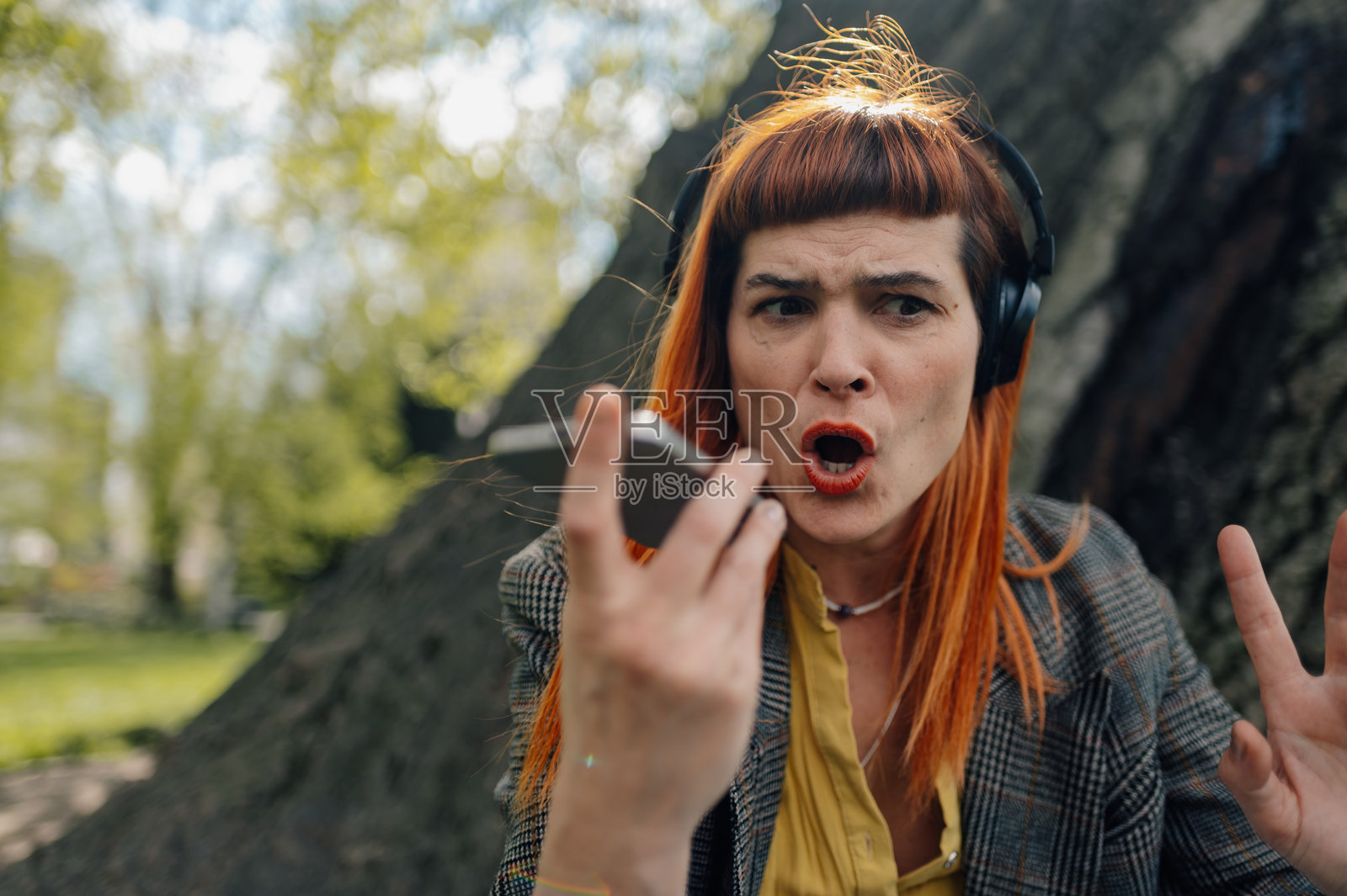 愤怒的女商人在公园里大声用手机喊叫照片摄影图片