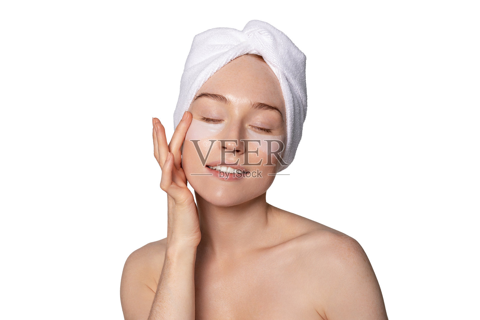 年轻女性在明亮的环境中用头巾包着头，涂抹护肤产品，展现自我护理和美容日常。照片摄影图片