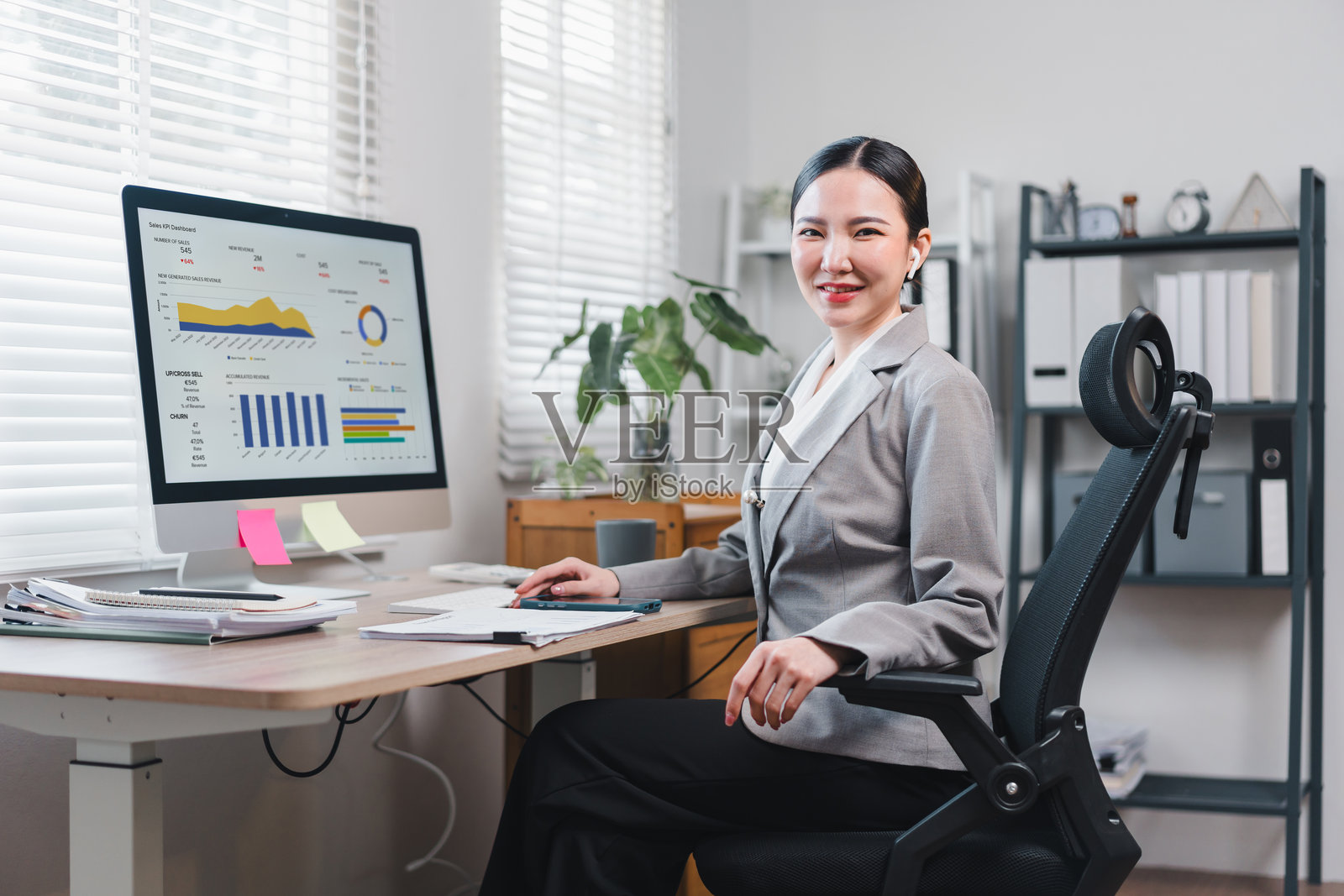 自信的亚洲女商人在现代办公室的桌子前坐着，正在分析电脑屏幕上的数据。照片摄影图片