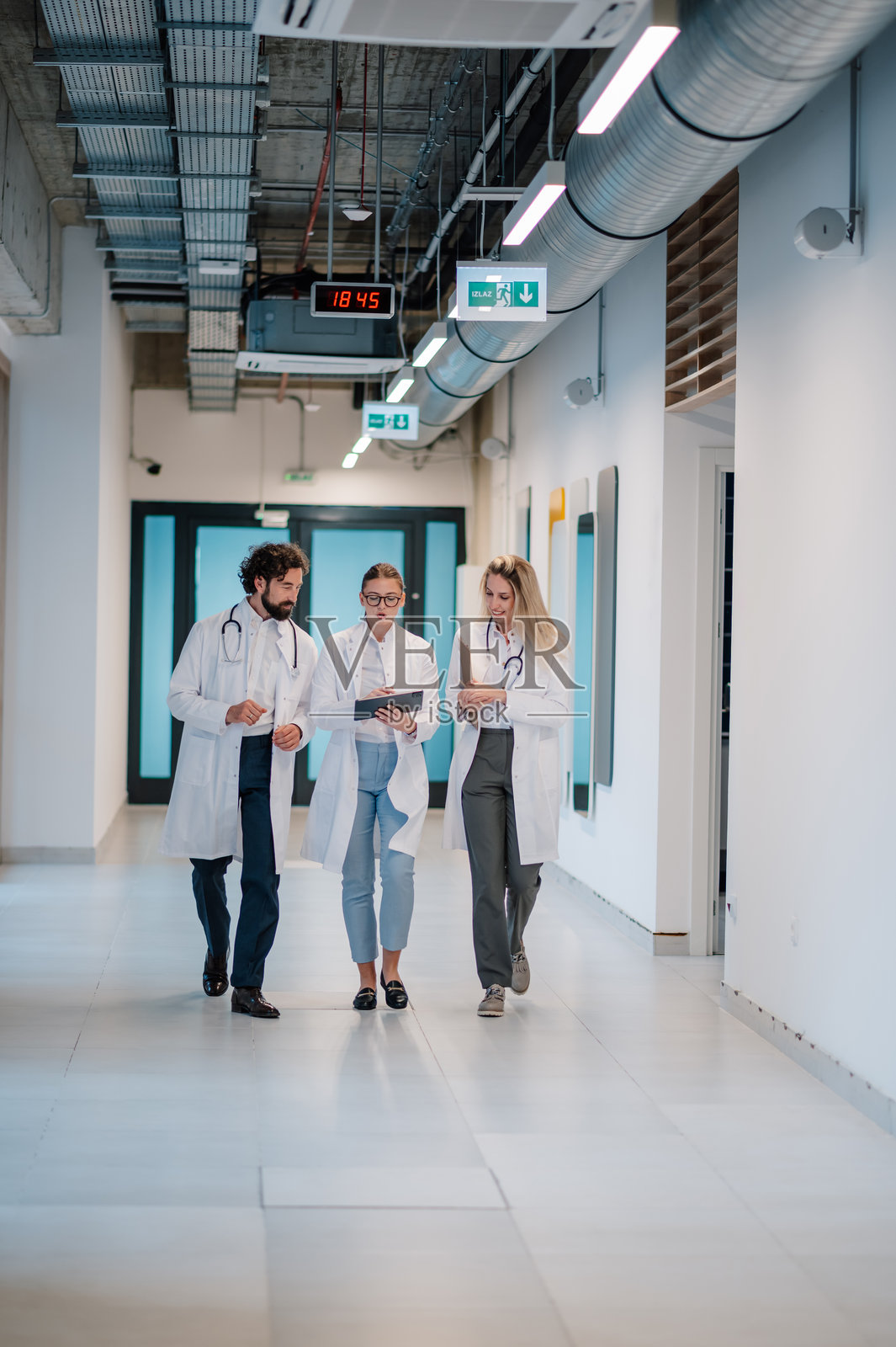 医生在医院走廊里走动并讨论病人的诊断照片摄影图片