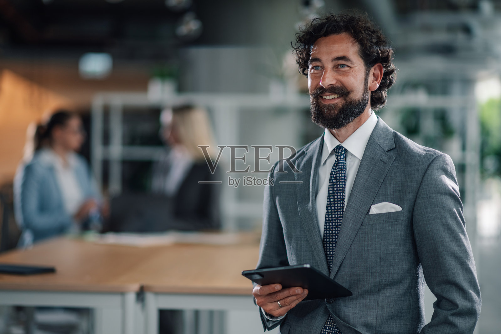 微笑的商人在现代办公室里拿着数字平板电脑照片摄影图片