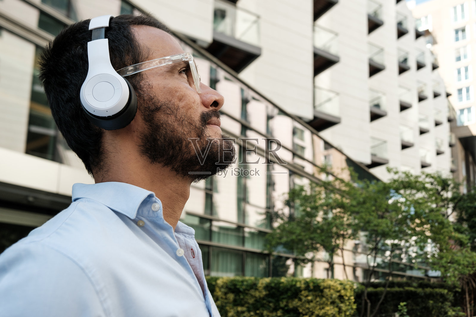 商人戴着耳机在城市中走路听音乐照片摄影图片