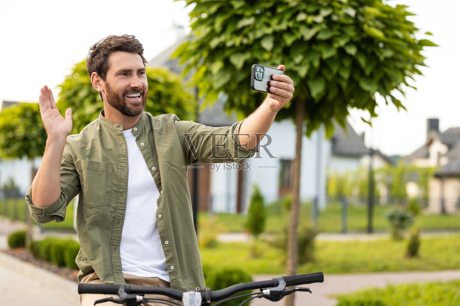 留着胡子的年轻男子正在进行视频通话，面带微笑。照片摄影图片