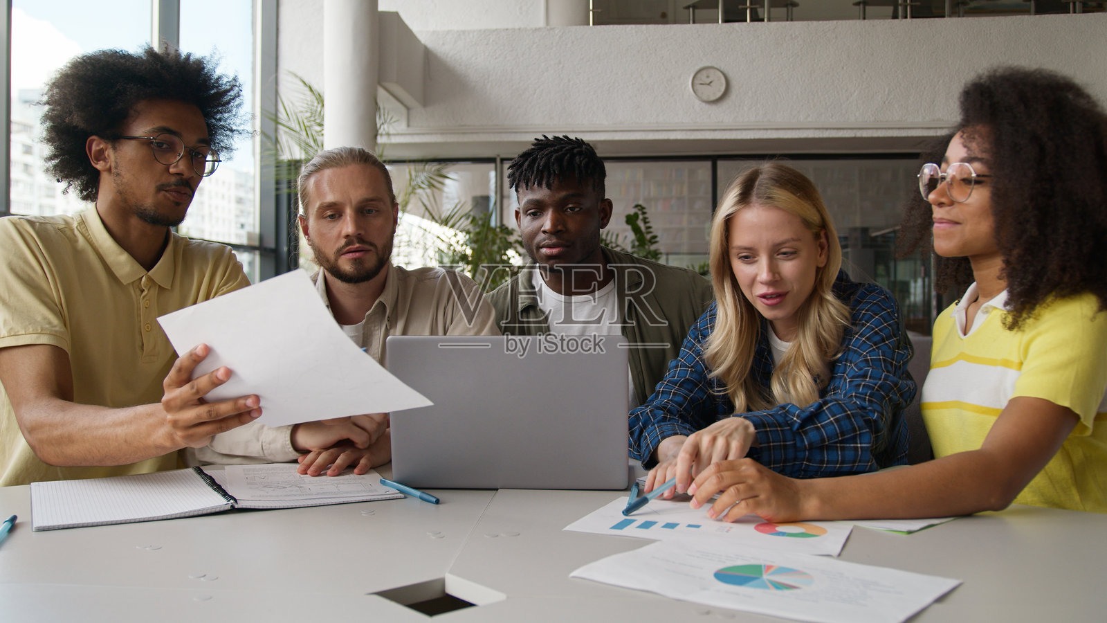 一群多种族的学生在一起进行在线学习，男女学生在大学里聚集，使用笔记本电脑，欢笑交谈，讨论话题，准备考试。照片摄影图片