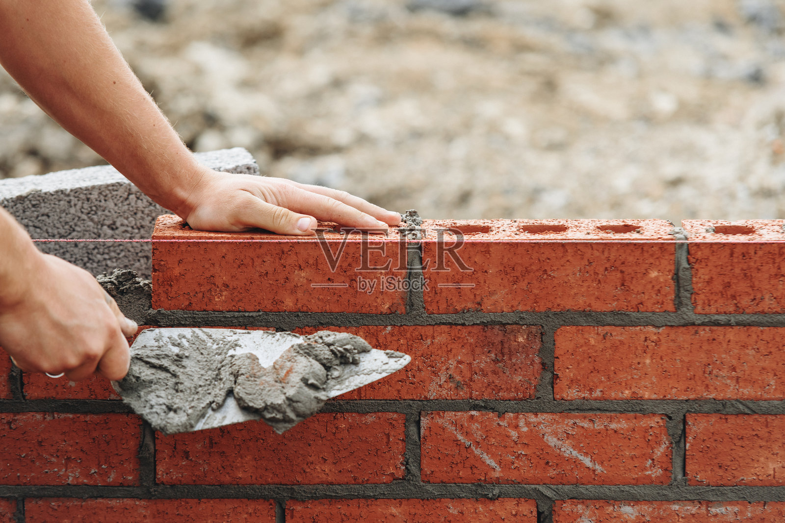 熟练的砖瓦工在建筑工地上铺设砖块，进行墙体施工的特写镜头照片摄影图片
