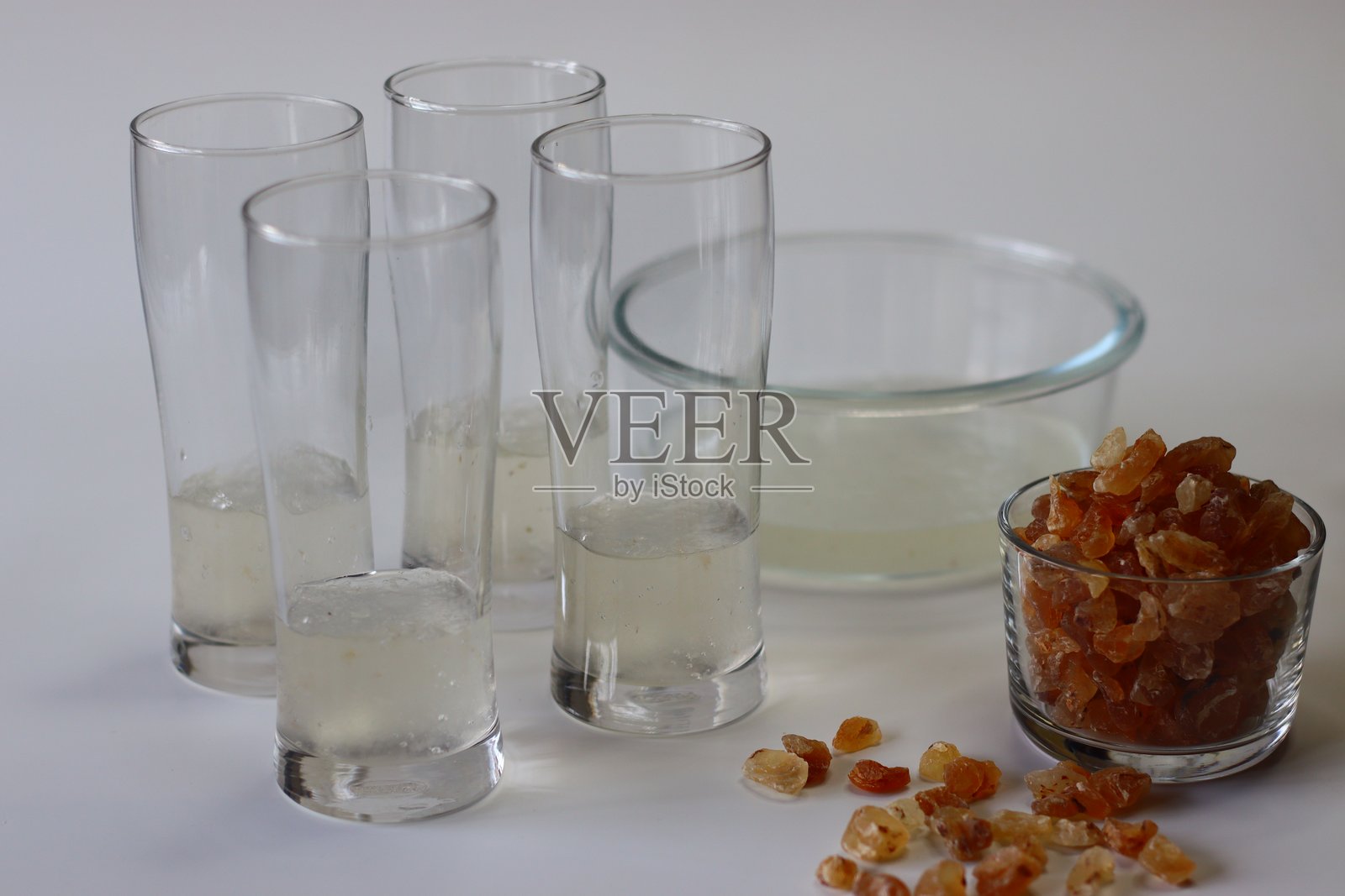冷却的甘草水，使用浸泡过的树胶晶体制成，盛在高脚杯中，旁边有一碗果冻状的晶体。照片摄影图片