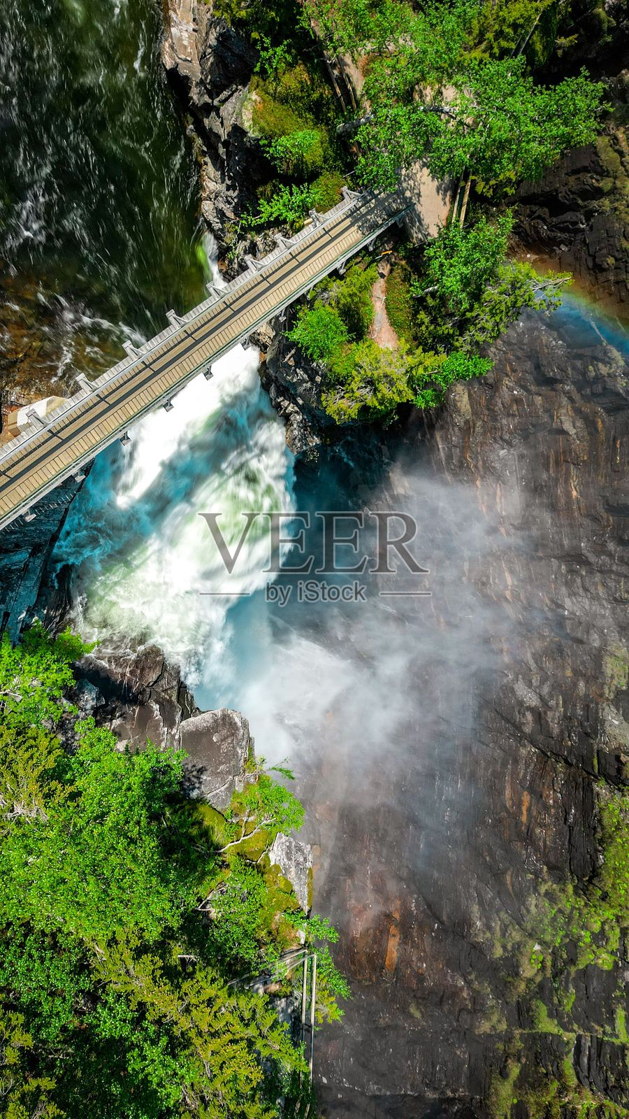 瀑布和桥的鸟瞰图，伴有彩虹雾气。照片摄影图片