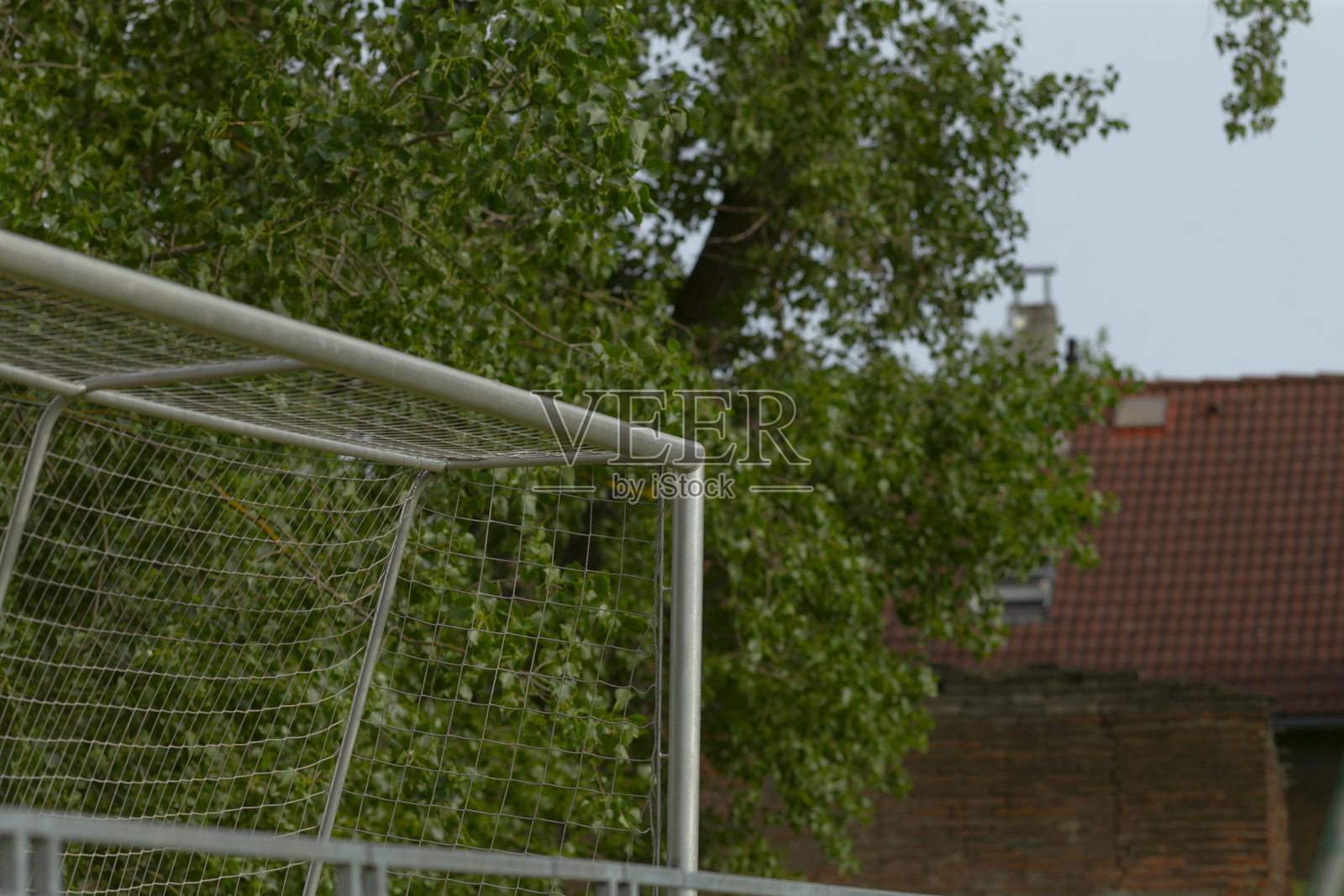 一个足球门位于树木和建筑物的背景中。照片摄影图片