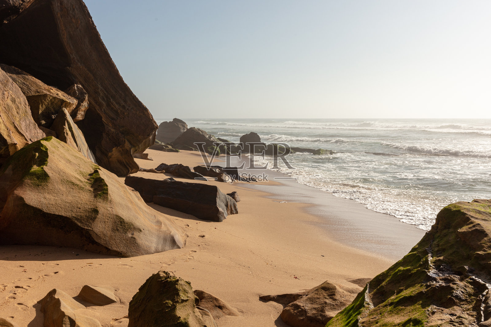 日出时分，岩石海滩上有砂岩巨石和海浪照片摄影图片