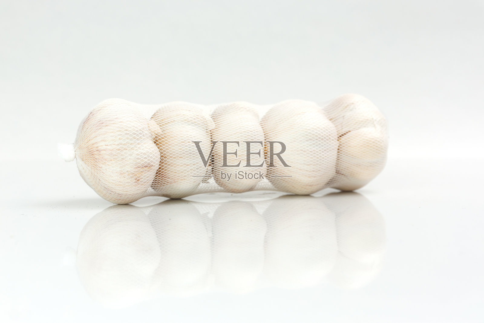 网袋中的大蒜头 - 背景为白色照片摄影图片