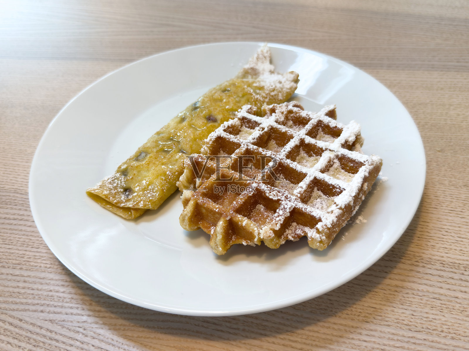 美味的可丽饼和华夫饼，撒上糖粉，摆放在木桌上照片摄影图片