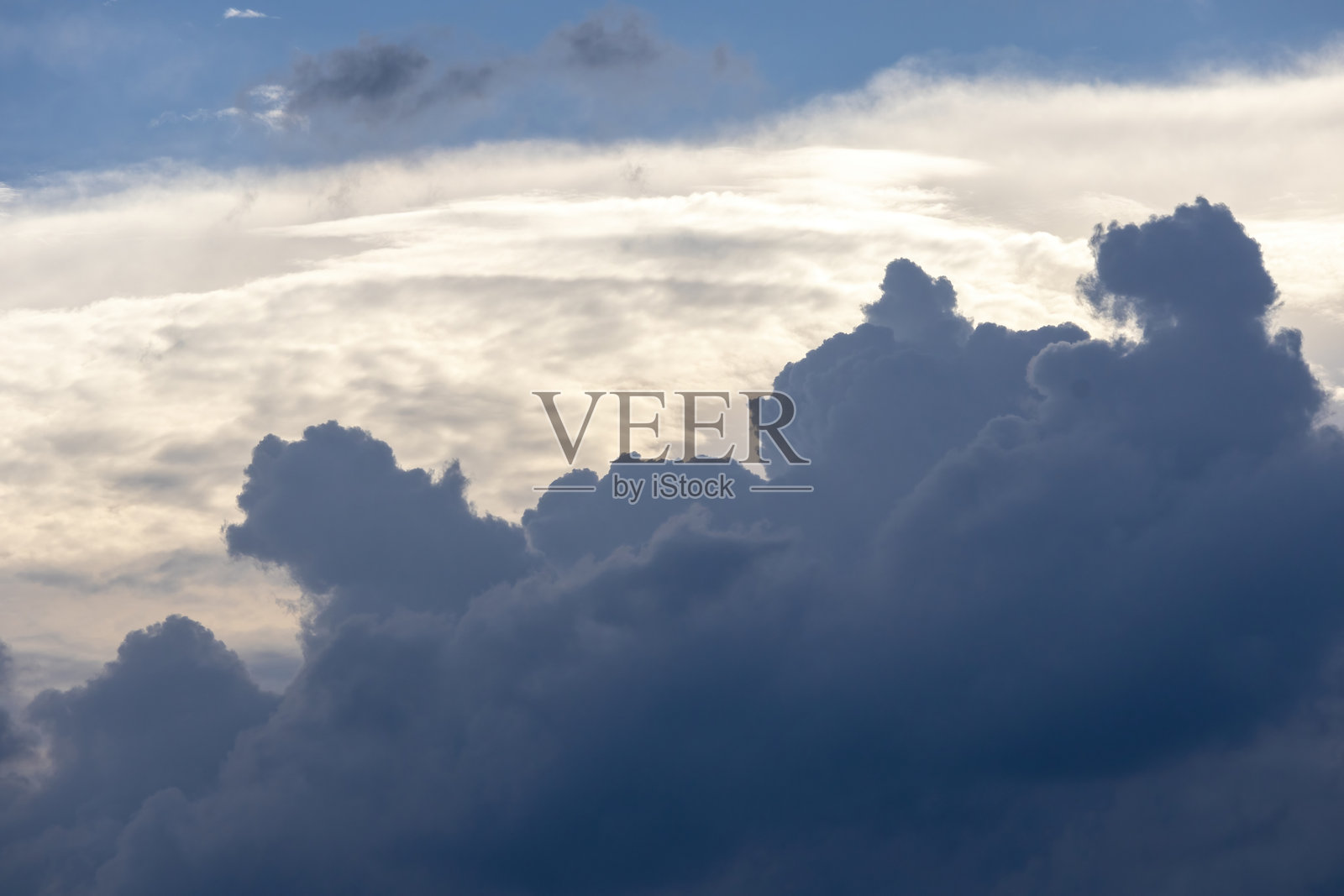 戏剧性的下午天空，雄伟的深灰色积云与迅速移动的白云形成鲜明对比。美丽的阳光天气场景，非常适合自然和天气主题。照片摄影图片