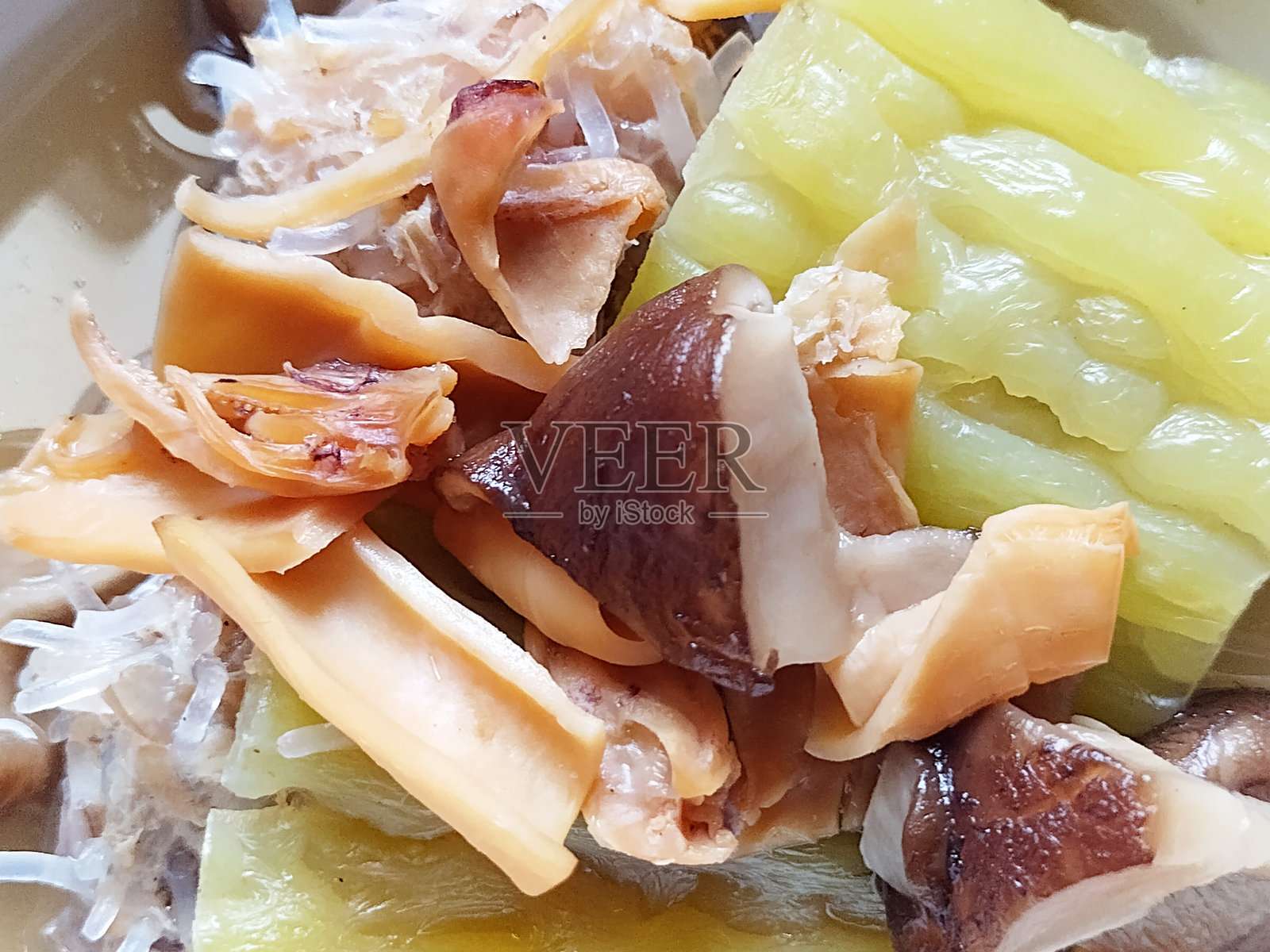诱人的清汤特写，突显嫩滑的酿苦瓜、香 earthy 的香菇和水发的美味干鱿鱼丝。照片摄影图片