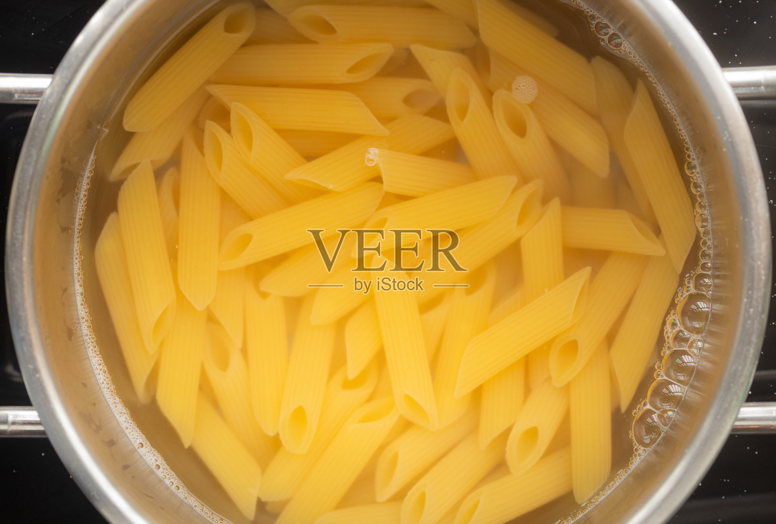 生的通心粉在锅中沸水中煮。照片摄影图片