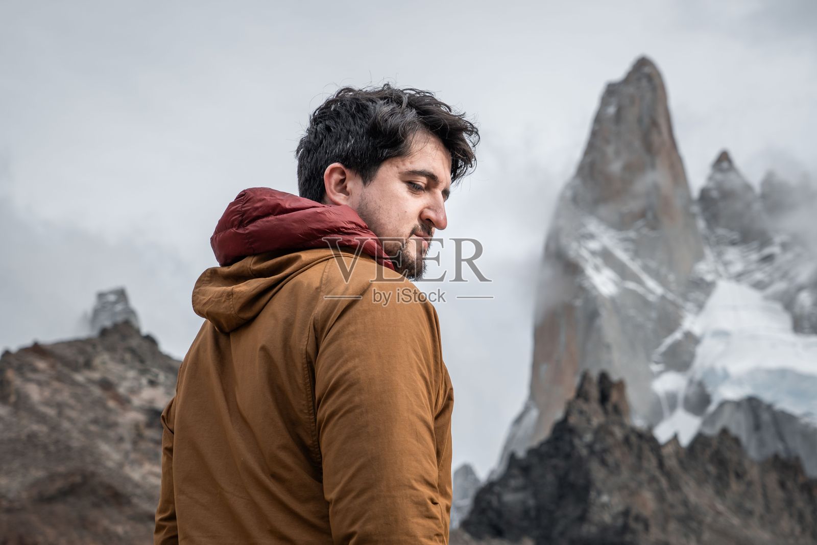 穿着棕色夹克的男子与山脉背景照片摄影图片