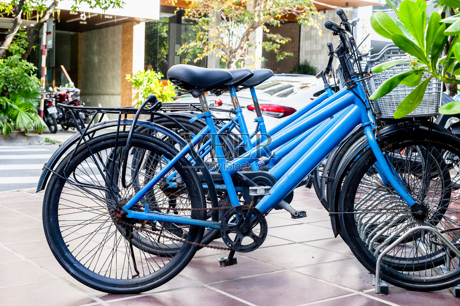 一排蓝色自行车停放在城市人行道上，展现户外交通场景照片摄影图片