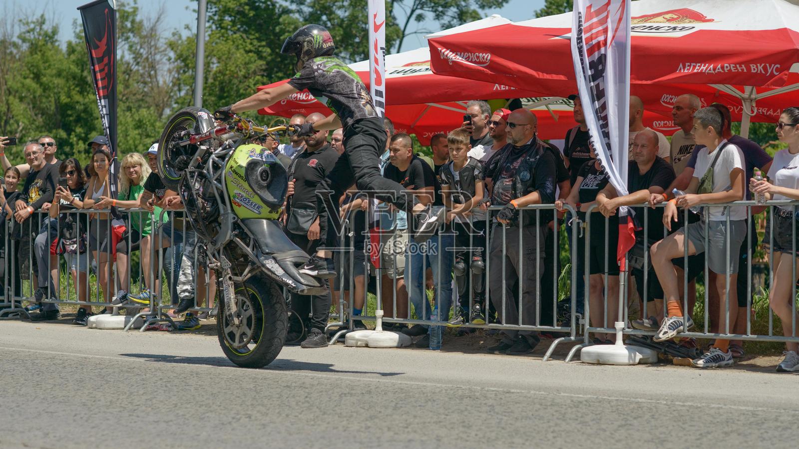 摩托车特技骑手在摩托摇滚节上表演单脚轮胎特技照片摄影图片