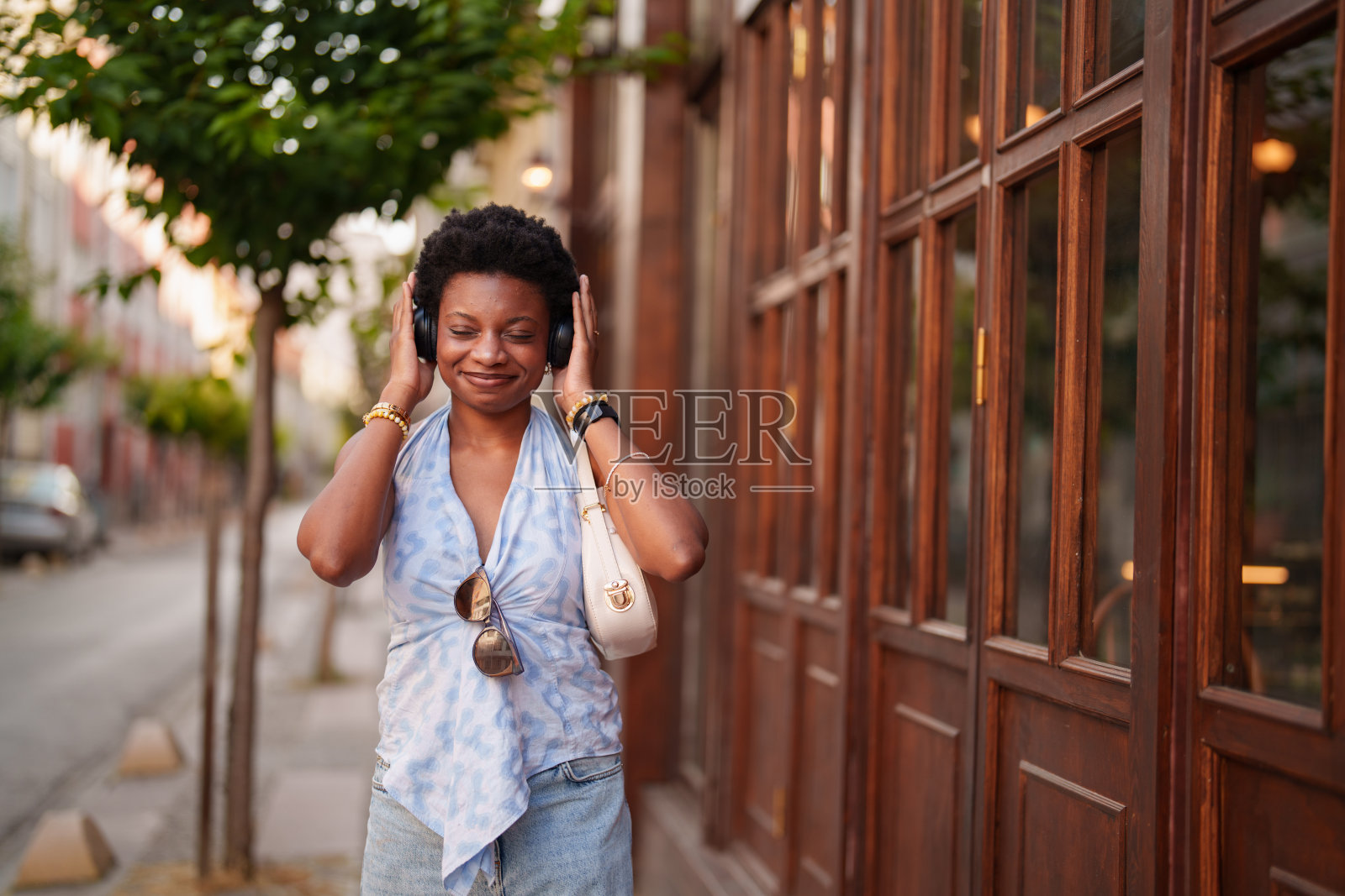 年轻女性在城市街道上走着，戴着耳机照片摄影图片