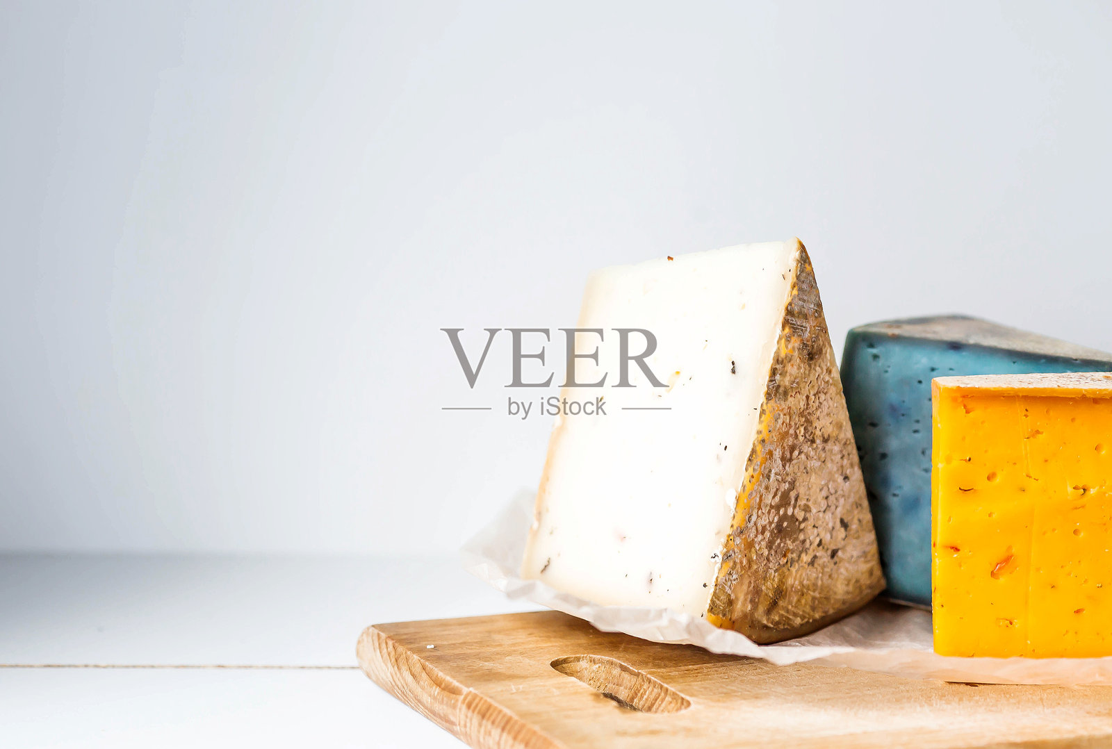 新鲜、陈年、天然农场奶酪片放在木板上的羊皮纸上。农场新鲜农产品独特的味道和品质。照片摄影图片