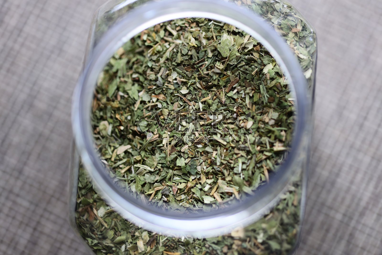 一个装满干草药的罐子放在桌子上，非常适合用于静物摄影或作为装饰元素。照片摄影图片