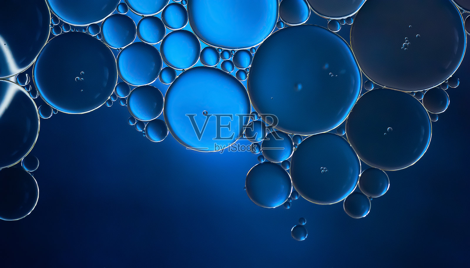 油泡。深蓝色调下水面上的油泡特写。抽象纹理。照片摄影图片