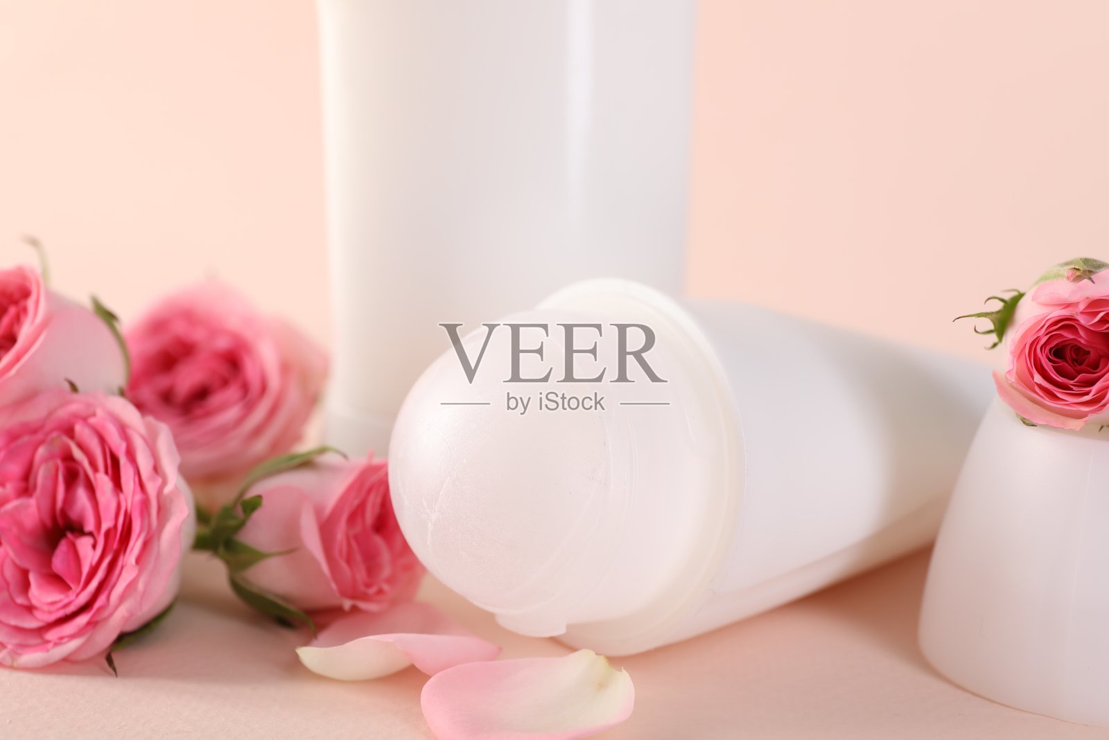 不同的除臭剂和美丽的玫瑰花在米色背景上，特写镜头照片摄影图片