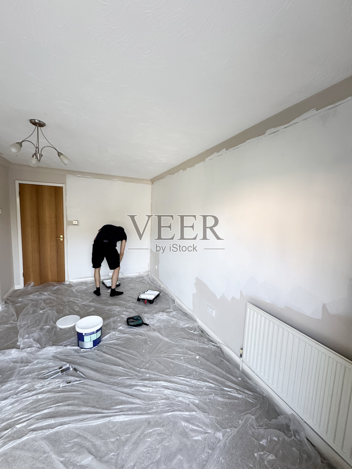 男人在重新装修时高兴地大喊，使用白色滚筒涂刷墙壁，室内设计项目，家庭改善，DIY。照片摄影图片