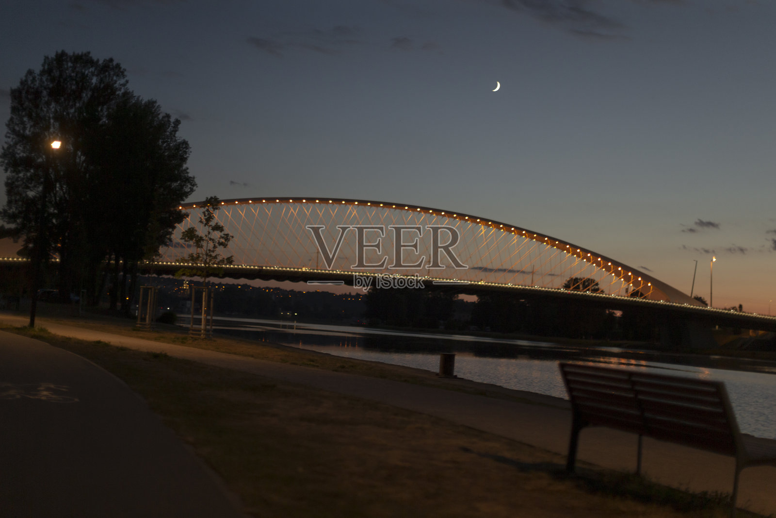 黄昏和夜晚时分，宁静水面上美丽的灯光桥梁照片摄影图片