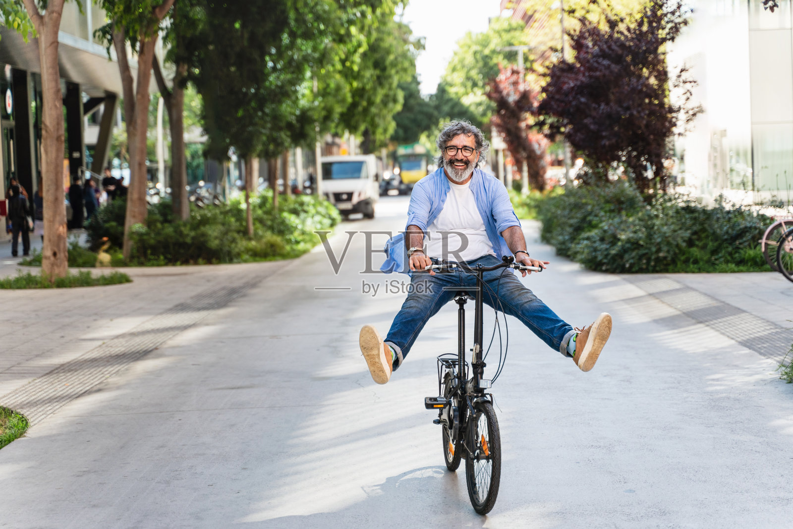 无忧无虑的老年男子在城市中骑着有趣的自行车，享受快乐的退休生活。照片摄影图片
