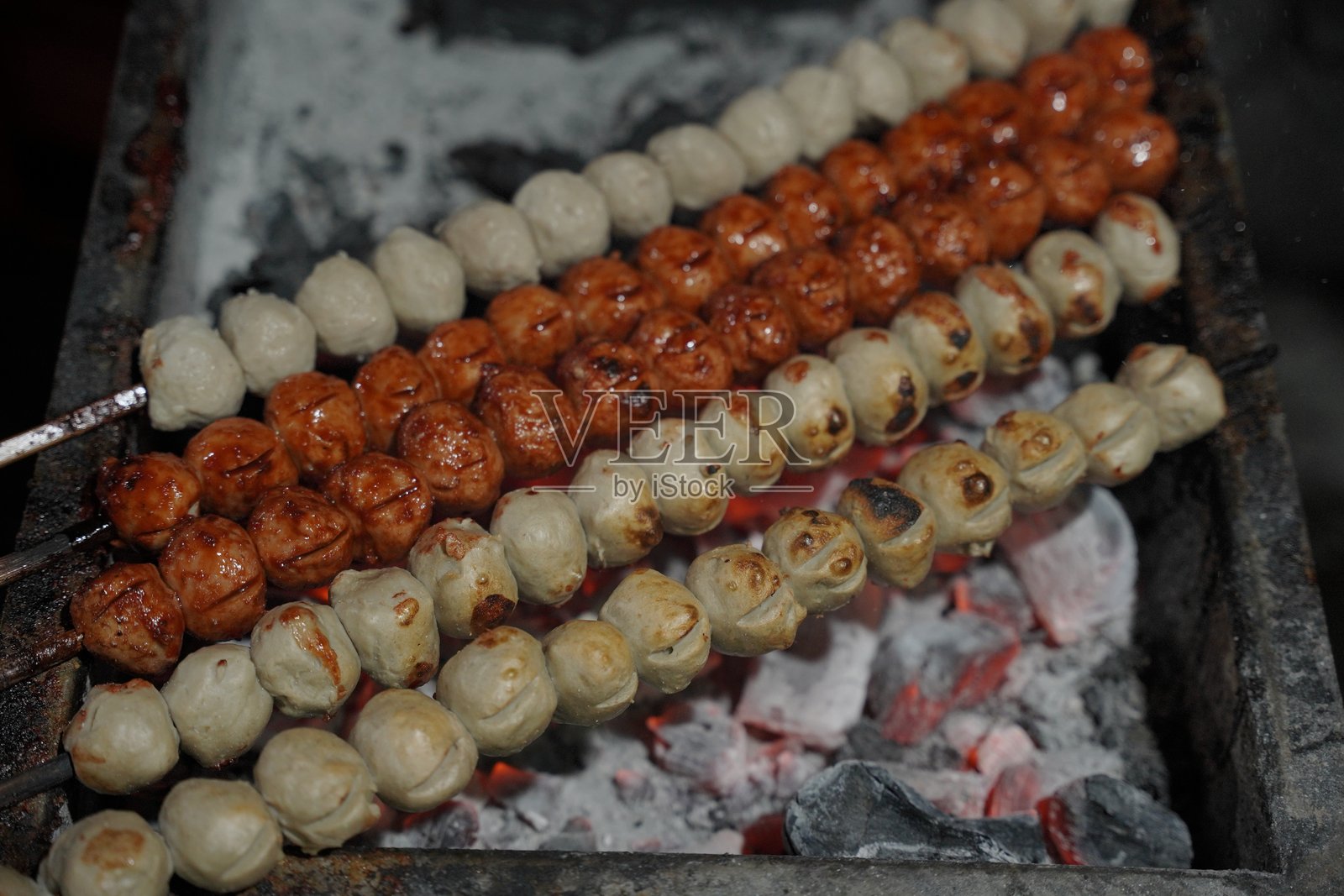烤肉丸，卖家正在烤制肉丸。烤肉丸或烤肉球，印尼街头美食，便宜又美味。照片摄影图片