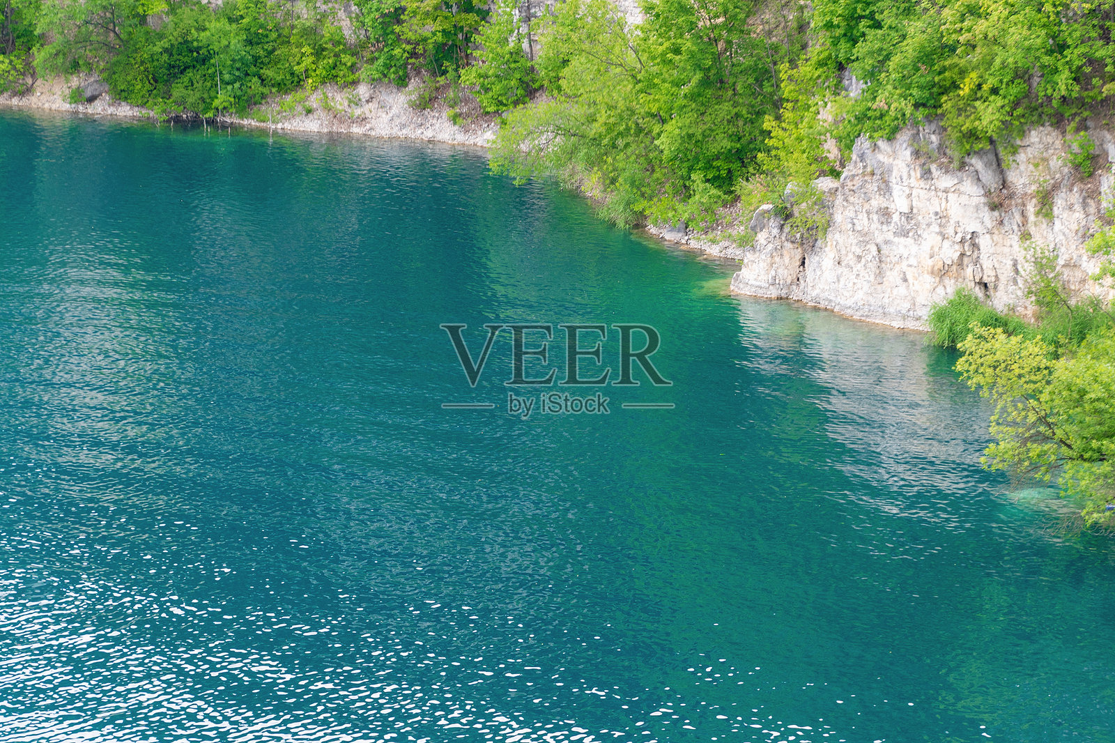 清澈的蓝色湖泊被绿色树木和岩石悬崖环绕照片摄影图片