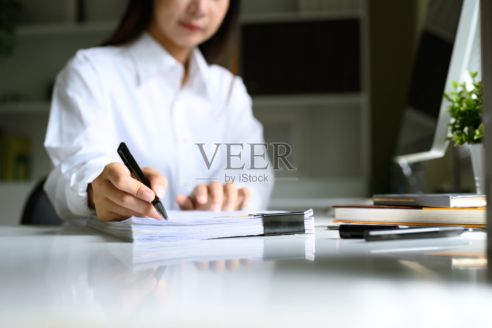 女性在办公桌上仔细审阅并签署一叠文件的特写镜头照片摄影图片
