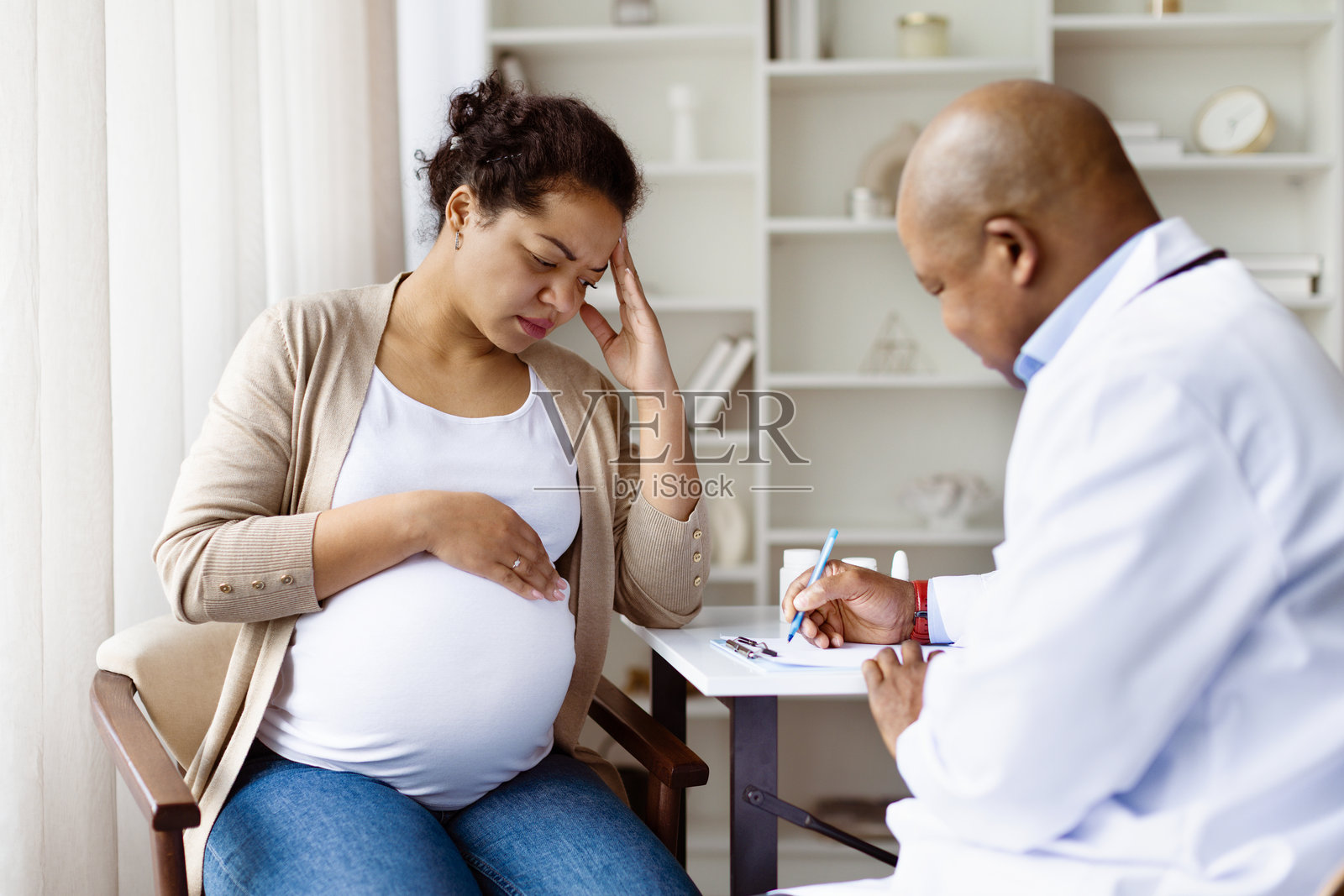 孕妇在产前就诊时触摸太阳穴，感到头痛照片摄影图片