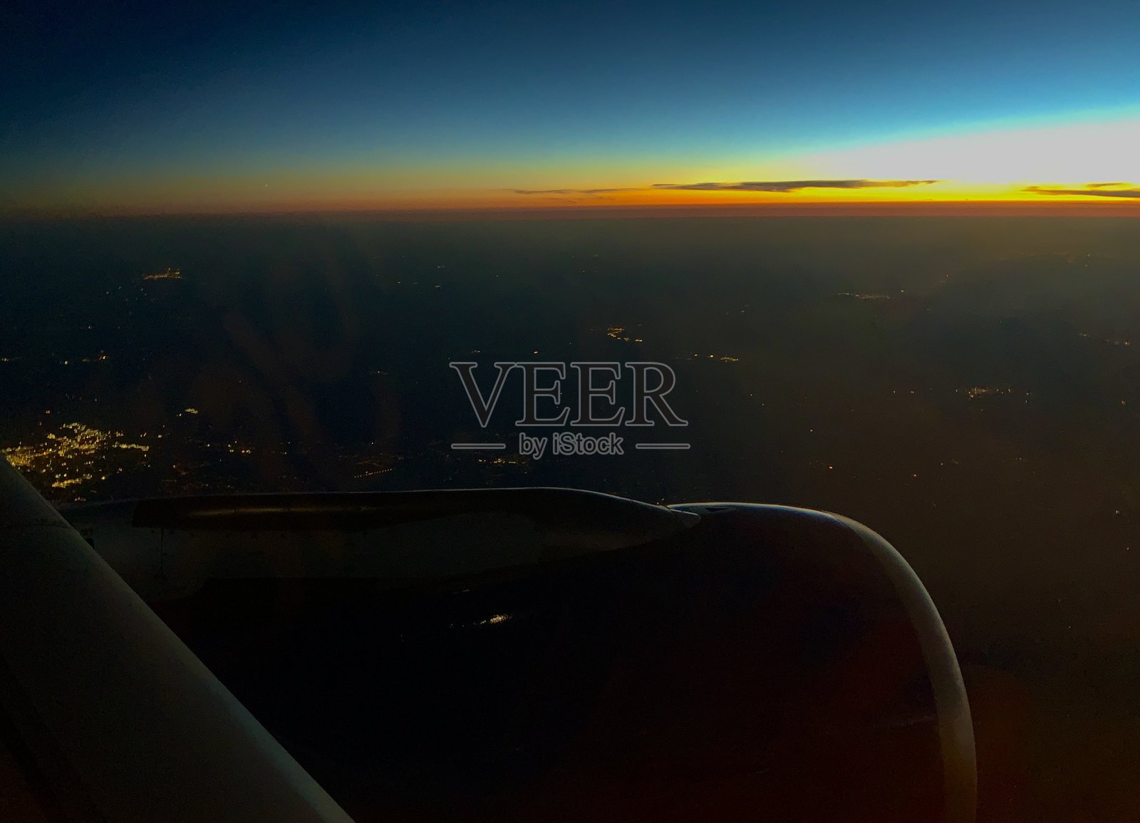 从飞机窗户俯瞰日落时穿破云层的景象，带有机翼视角照片摄影图片