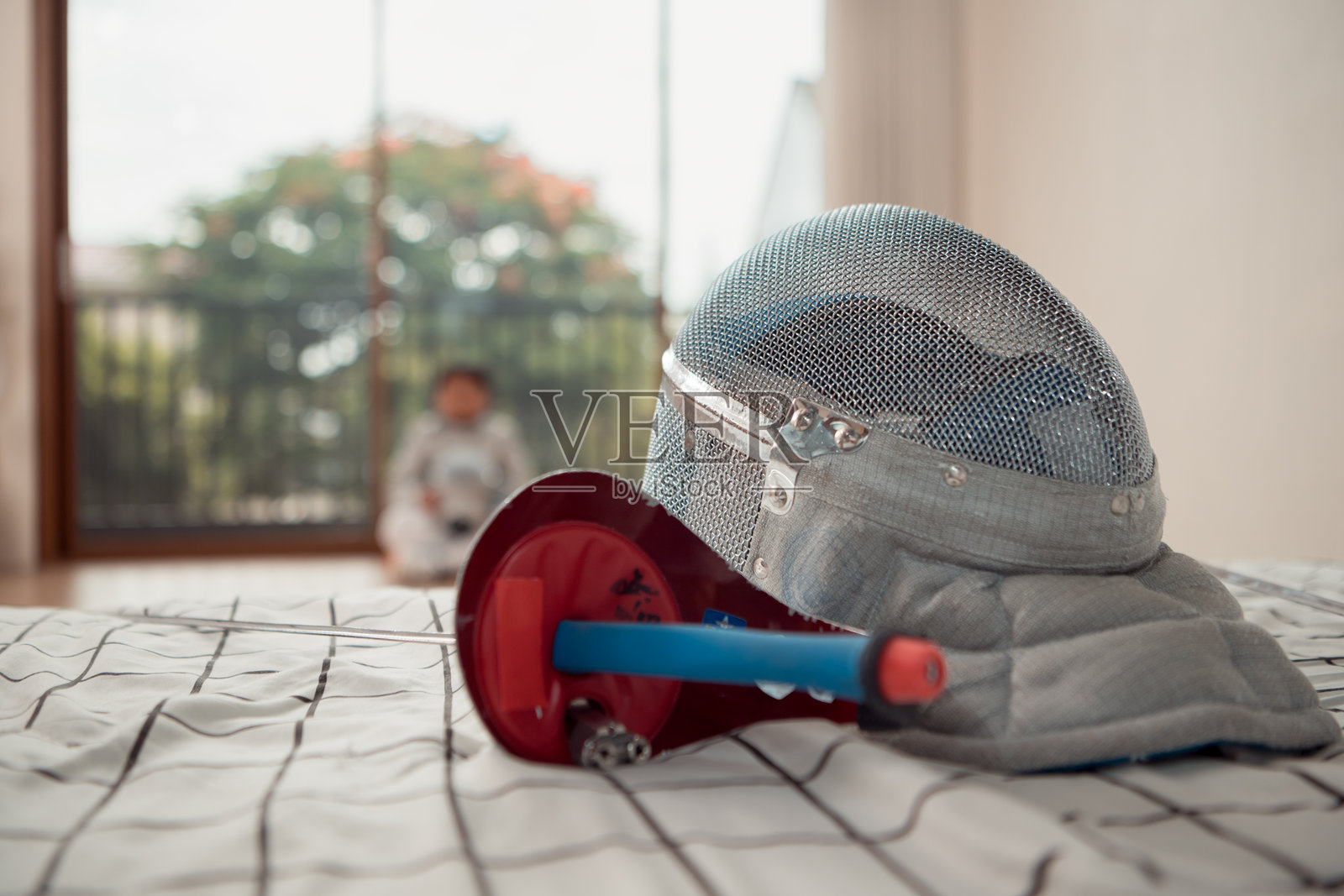 在比赛日之前，一个穿着击剑装备的男孩正在健身房里排练。照片摄影图片