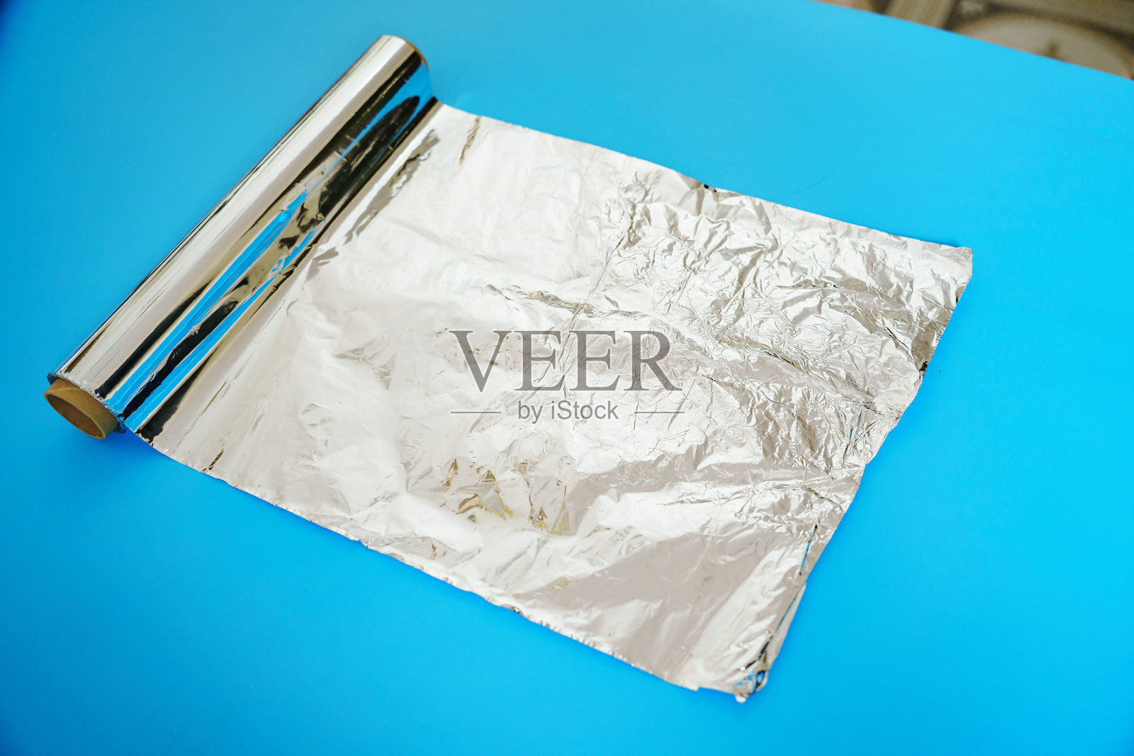 蓝色背景上的一卷烘焙铝箔。照片摄影图片