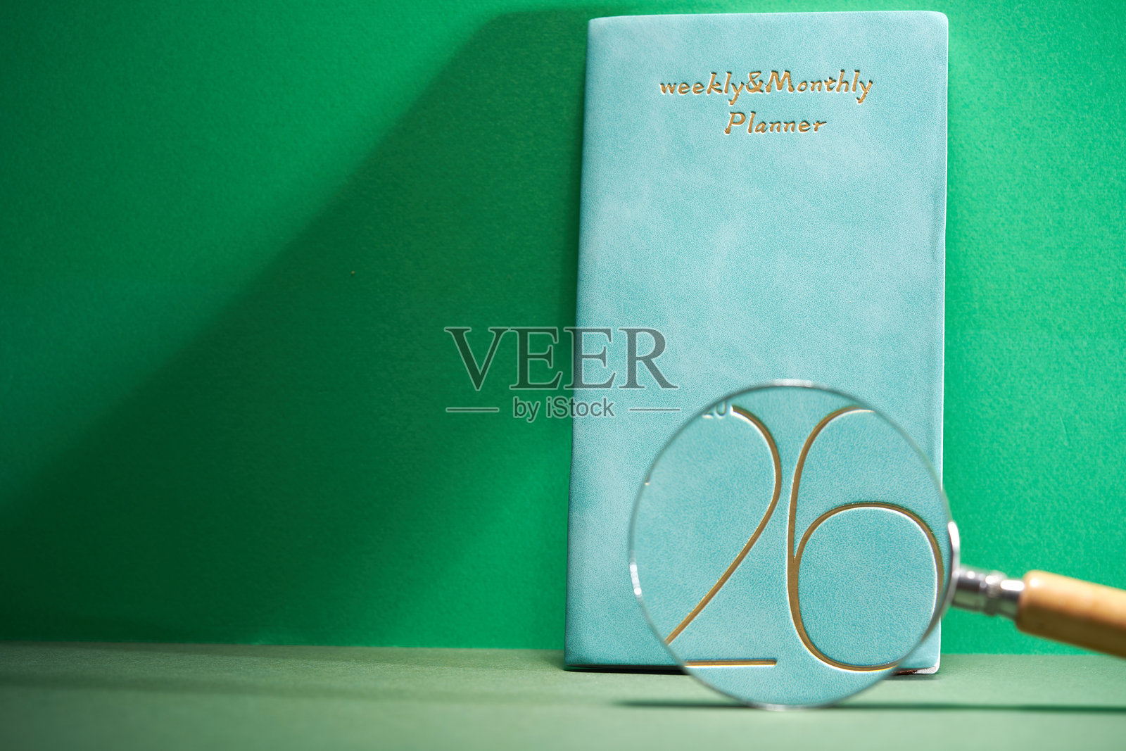 2026年计划本与放大镜置于绿色背景上照片摄影图片