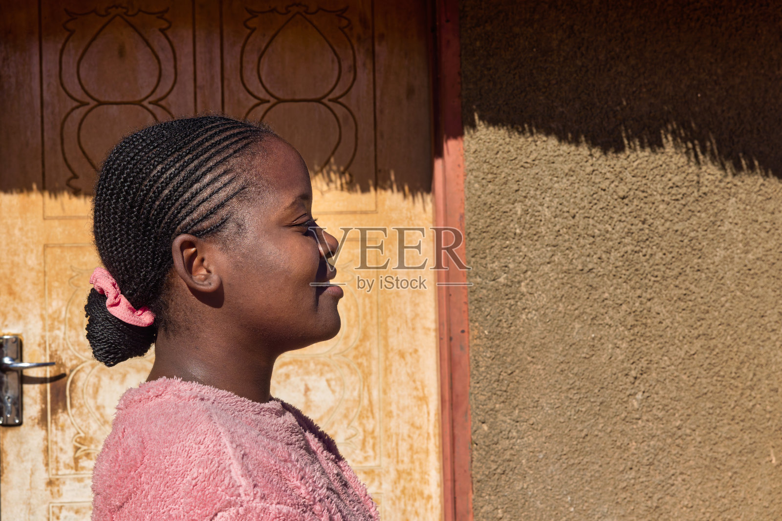 非洲村庄，留着辫子和脏辫的非洲女孩，站在房子前面照片摄影图片