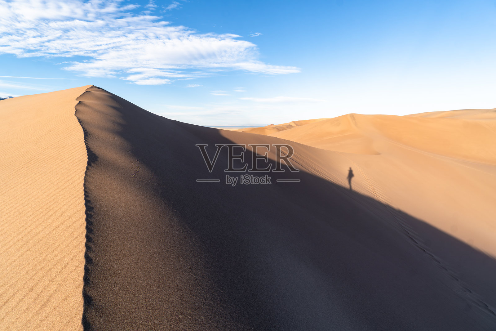 科罗拉多州大沙丘国家公园和保护区的沙丘山脊视角，背影是一位徒步旅行者的影子照片摄影图片