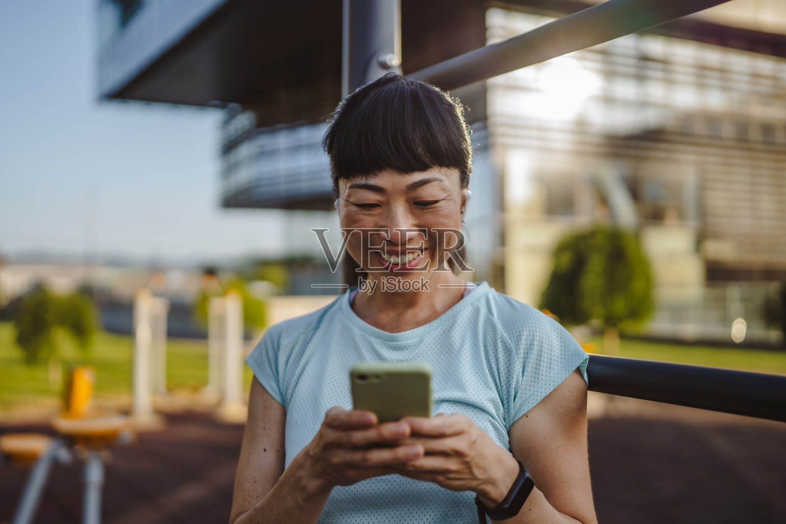 穿着运动服的日本女性在公园里站着使用手机照片摄影图片