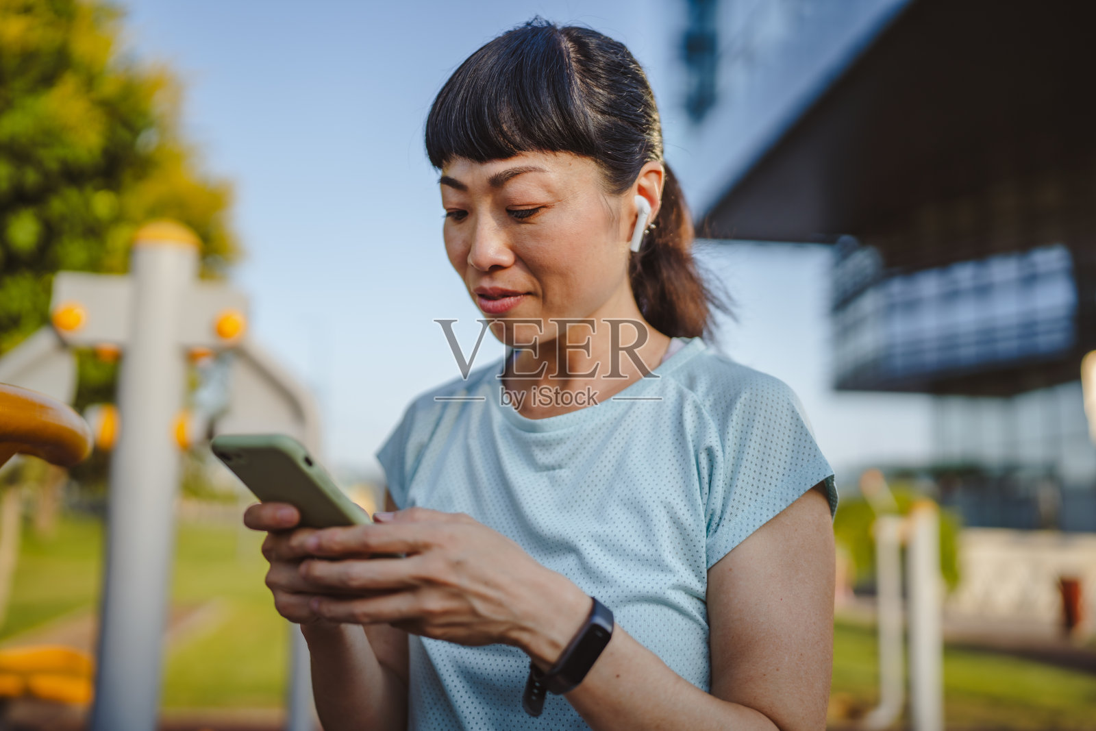穿着运动服的日本女性在公园里站着使用手机照片摄影图片