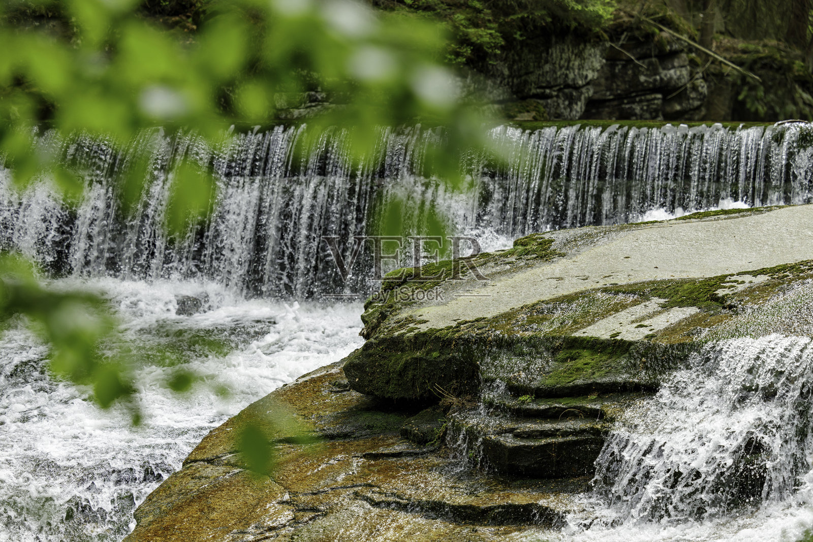 宁静的森林瀑布，清澈的溪流和苔藓覆盖的岩石照片摄影图片