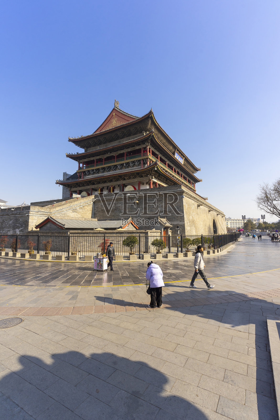 在中国西安,蓝天下的鼓楼前,有一些身份不明的人在旅行。照片摄影图片