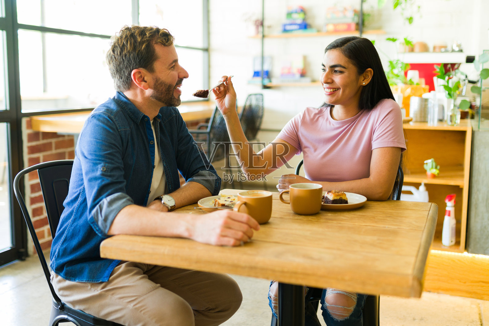 西班牙裔情侣在咖啡馆分享蛋糕和咖啡，享受浪漫约会照片摄影图片