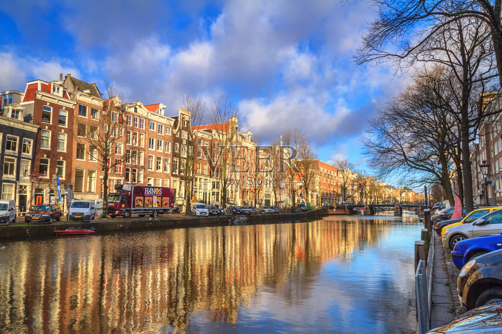 阳光明媚的冬日城市风景 - 阿姆斯特丹历史中心的房屋和城市运河，船只穿梭其间照片摄影图片
