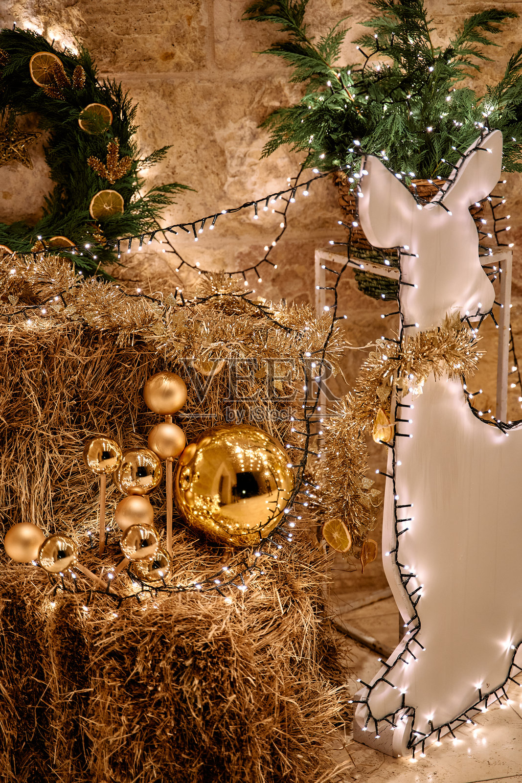 节日装饰，包含干草堆、金色饰品和发光的驯鹿雕像照片摄影图片