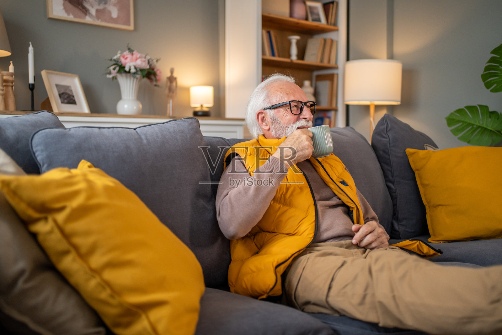 老年男子在家中沙发上放松，喝茶照片摄影图片